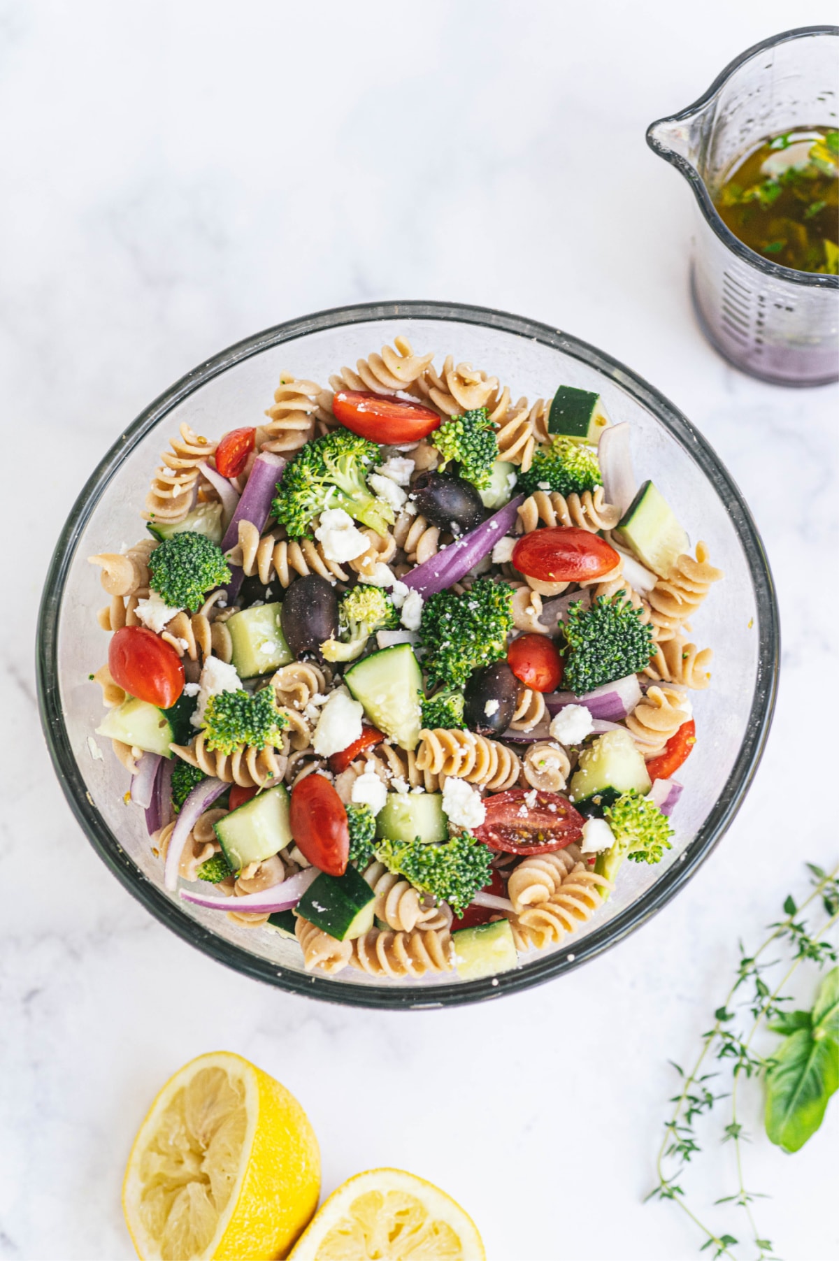 A large bowl of pasta veggie salad with dressing on the side.
