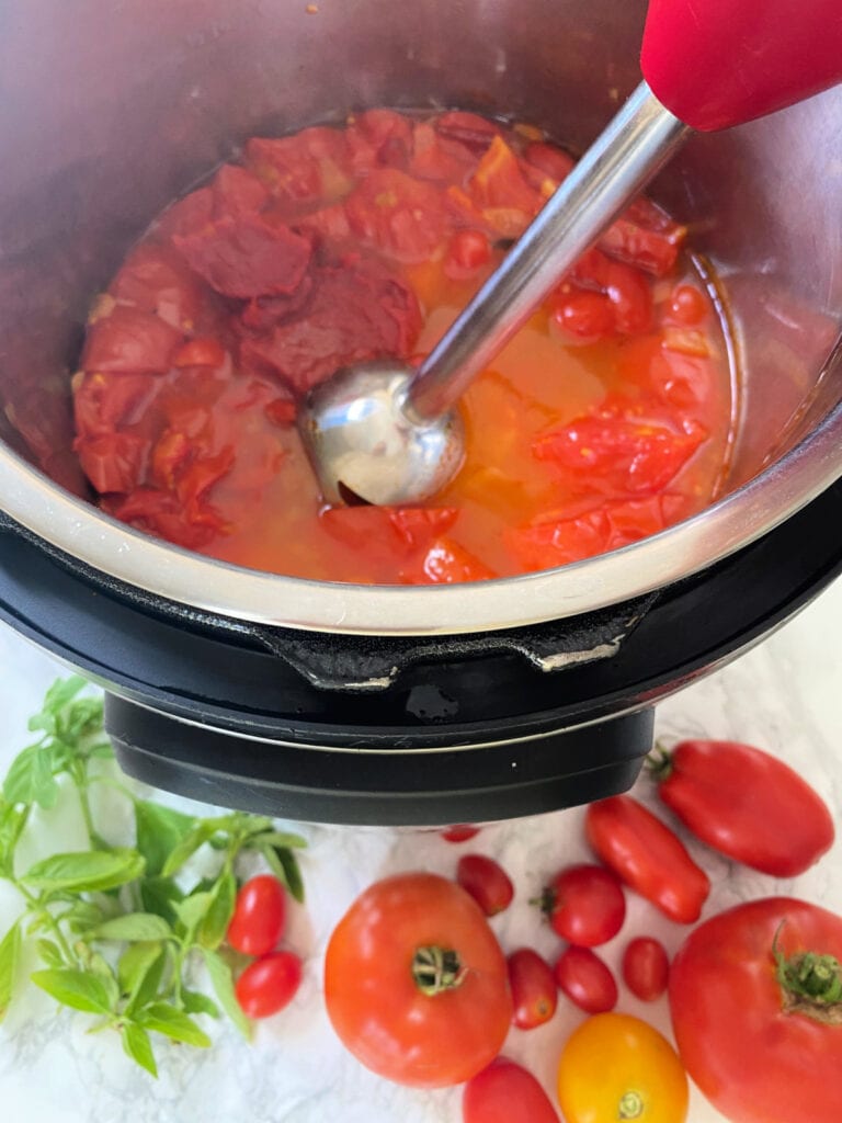 Cooked Instant Pot tomatoes with tomato paste and an immersion blender, ready to mix up some homemade sauce