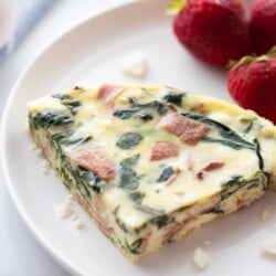 slice of Instant Pot frittata on white plate with fresh strawberries