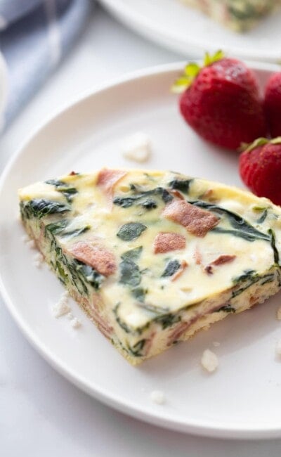 slice of Instant Pot frittata on white plate with fresh strawberries