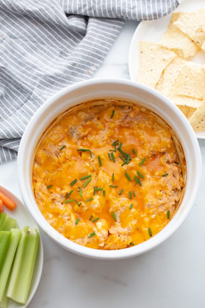Overhead photo of Healthy Buffalo Chicken Dip in a white casserole dish with dippers on the side.