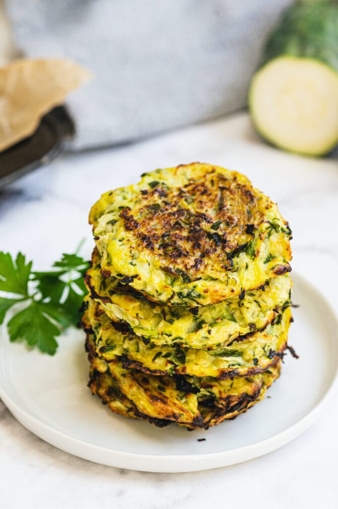 A stack of baked zucchini fritters on a small white plate