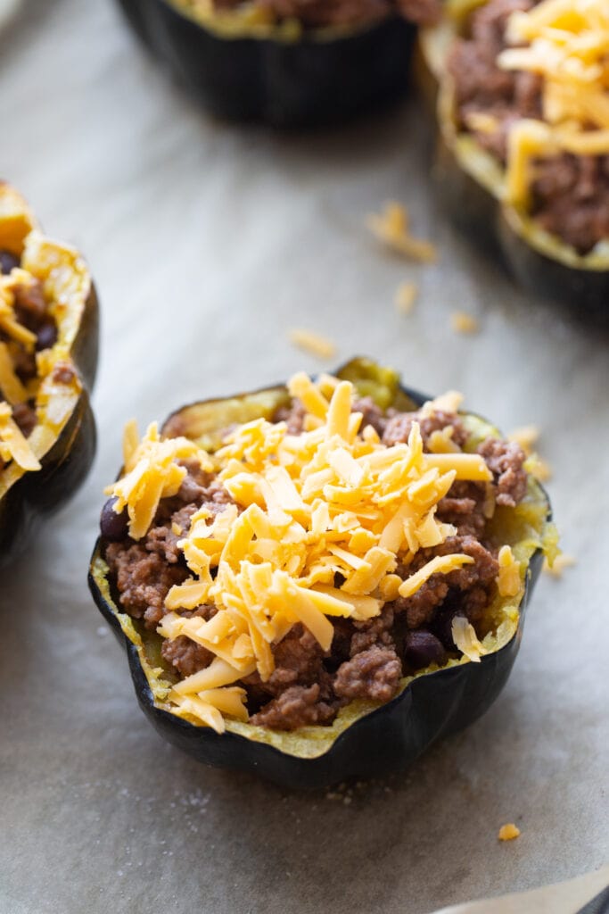 Acorn squash stuffed with taco meat and topped with cheese, ready to go back into the oven to melt the cheese.