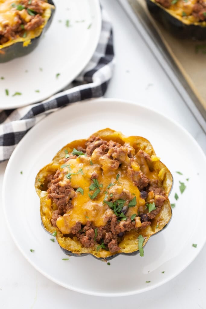 Overhead photo of a stuffed acorn squash with taco meat and cheese as a filling. 