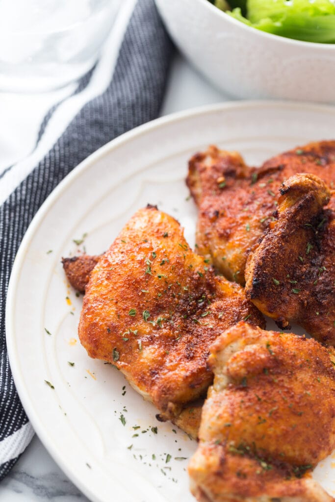 Crispy air fryer chicken thighs on white serving plate
