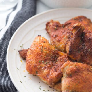 overhead photo: crispy air fried chicken thighs on a white plate