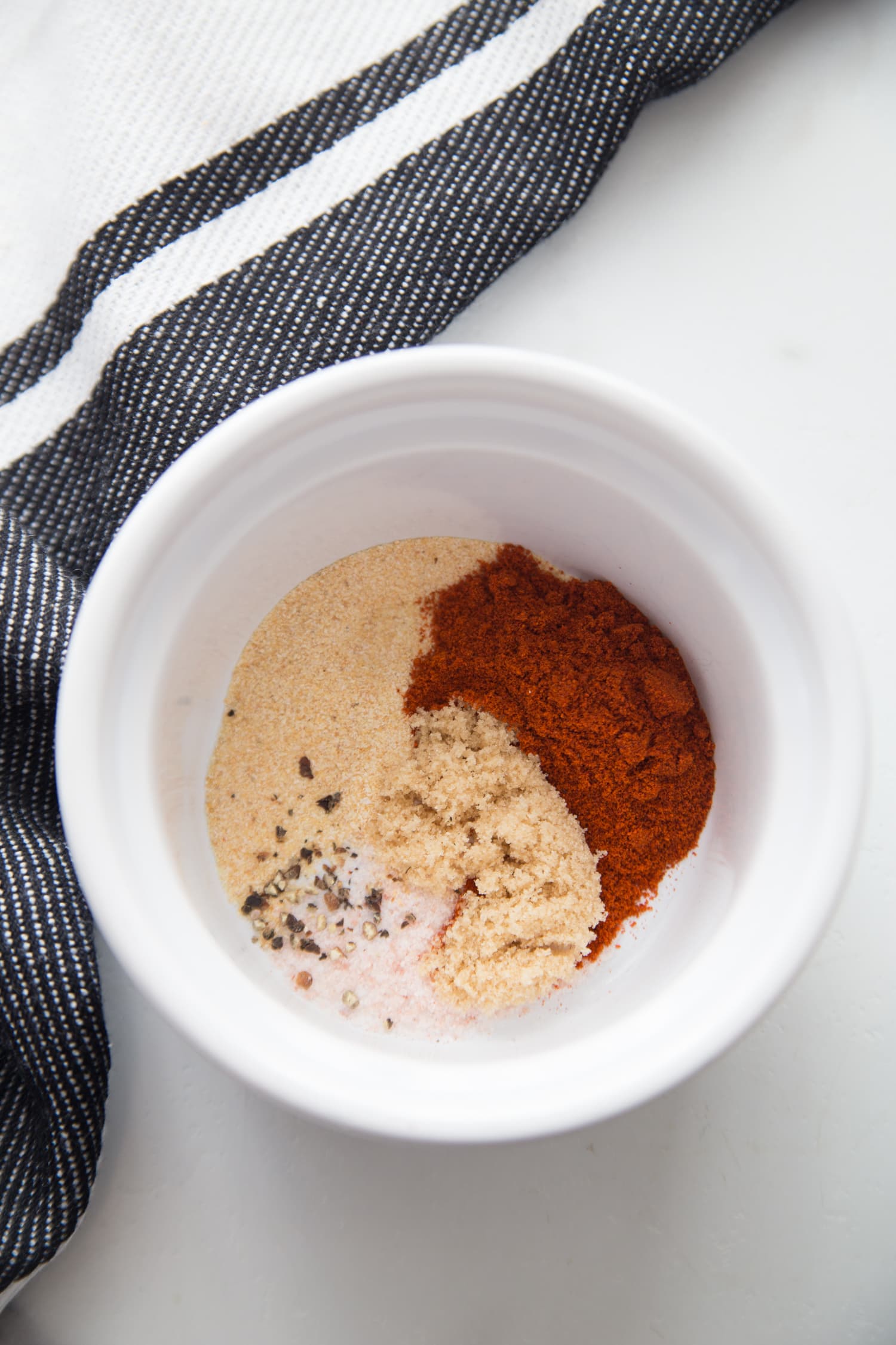 A small white bowl with dry rub for chicken thighs.
