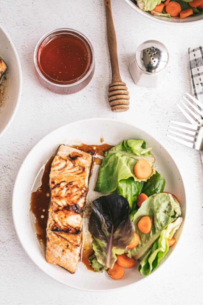 honey glazed salmon oven baked on a white plate with side salad