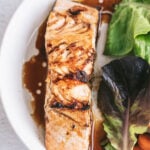 overhead closeup: salmon filet with teriyaki glaze on white plate with garden salad