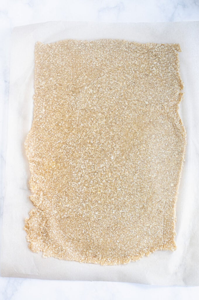 Overhead photo: parchment lined baking sheet with a rolled out crust for an apple tart, ready for the oven