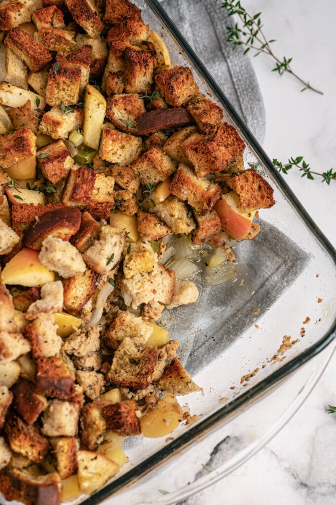 Overhead photo of a glass baking dish of stuffing with a portion missing from the corner.