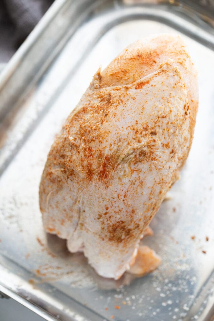 Seasoned turkey breast on a metal pan