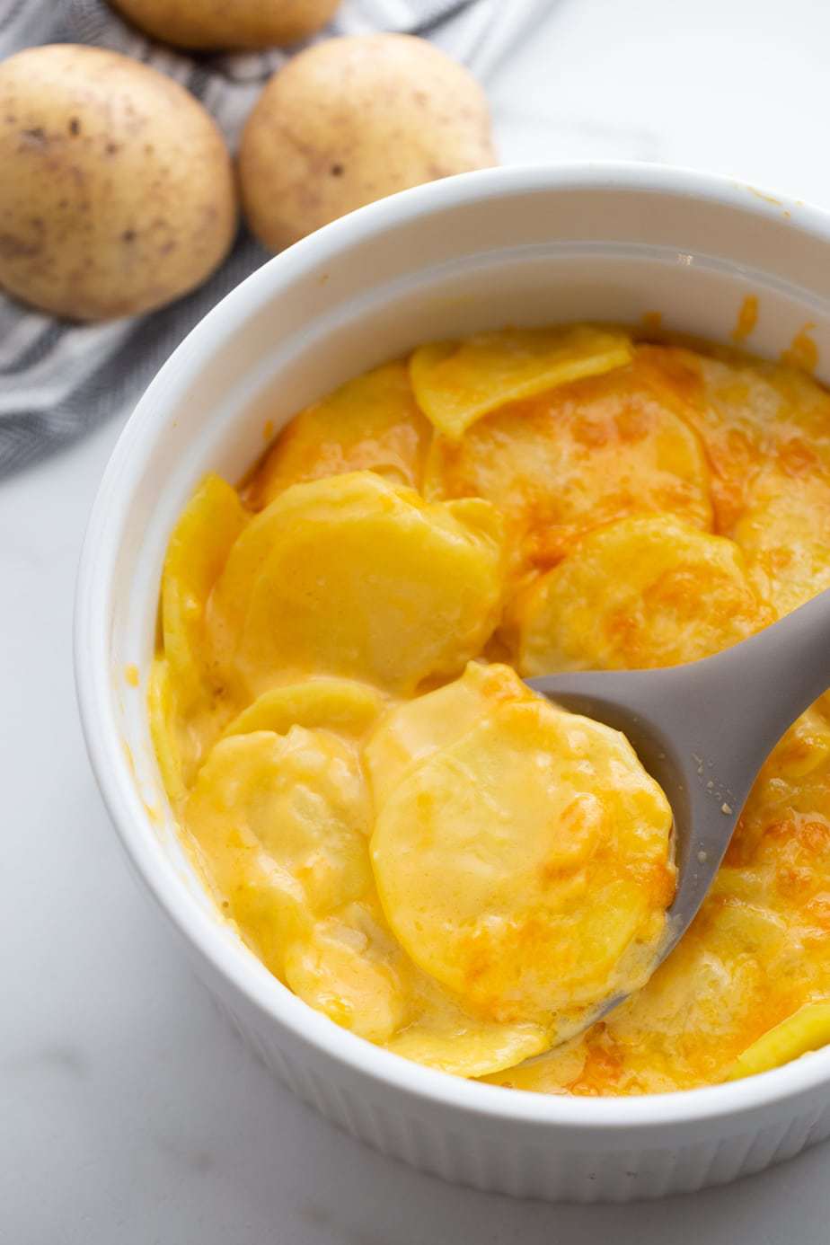Overhead image: sliced potatoes in cheese sauce, baked with a bubbly crispy top