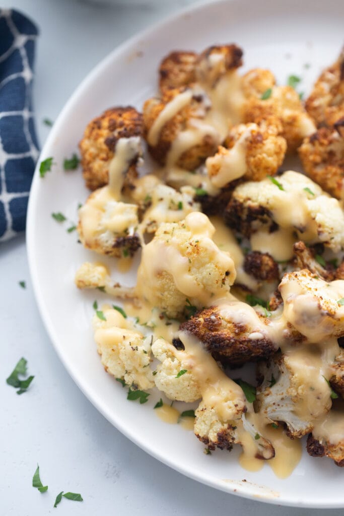 A plate of Crispy air fryer cauliflower drizzled with homemade cheese sauce