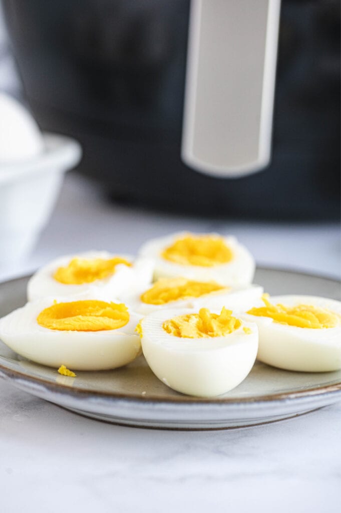 A plate of halved eggs is placed in front of the air fryer. 