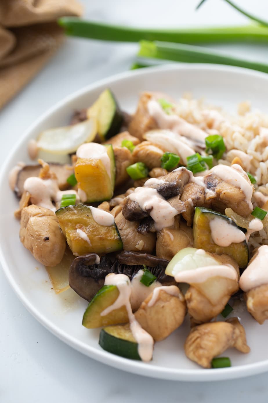 A white plate contains a serving of hibachi style chicken, veggies and rice.