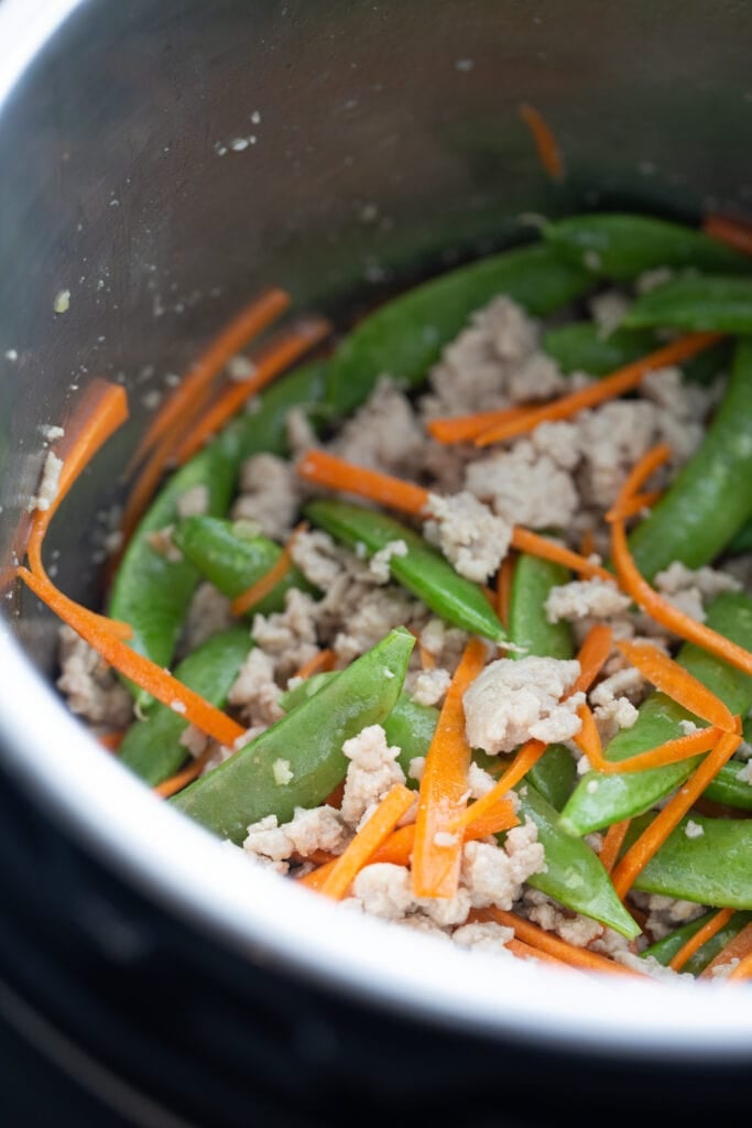 close up photo of matchstick carrots, snow peas and ground chicken in an Instant Pot