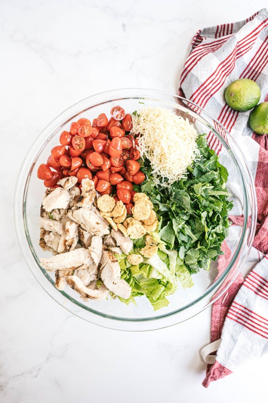 Overhead image: bowl of kale Caesar chicken salad, separated by ingredient