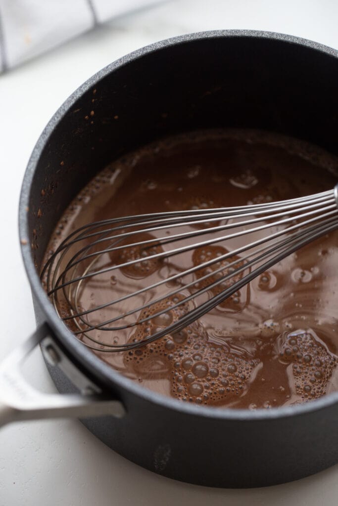 Homemade chocolate pudding being whisked in a saucepan
