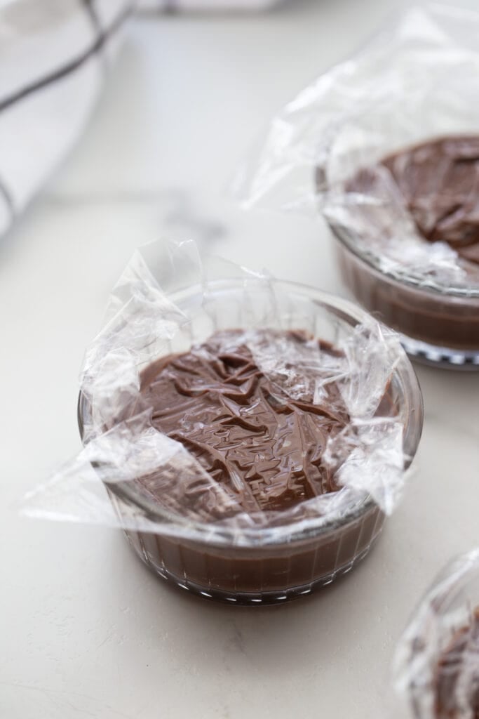 Small ramekins of vegan pudding topped with plastic wrap