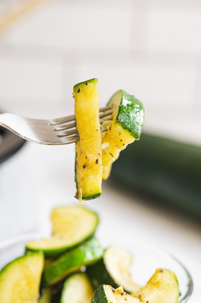 A close up of two pieces of sauteed zucchini on a fork 