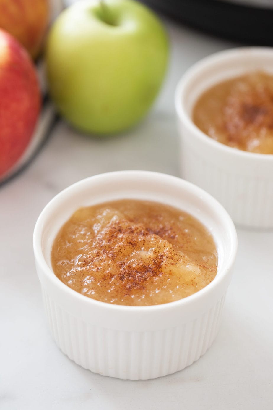 Two ramekins of homemade instant pot applesauce with cinnamon sprinkled on top 