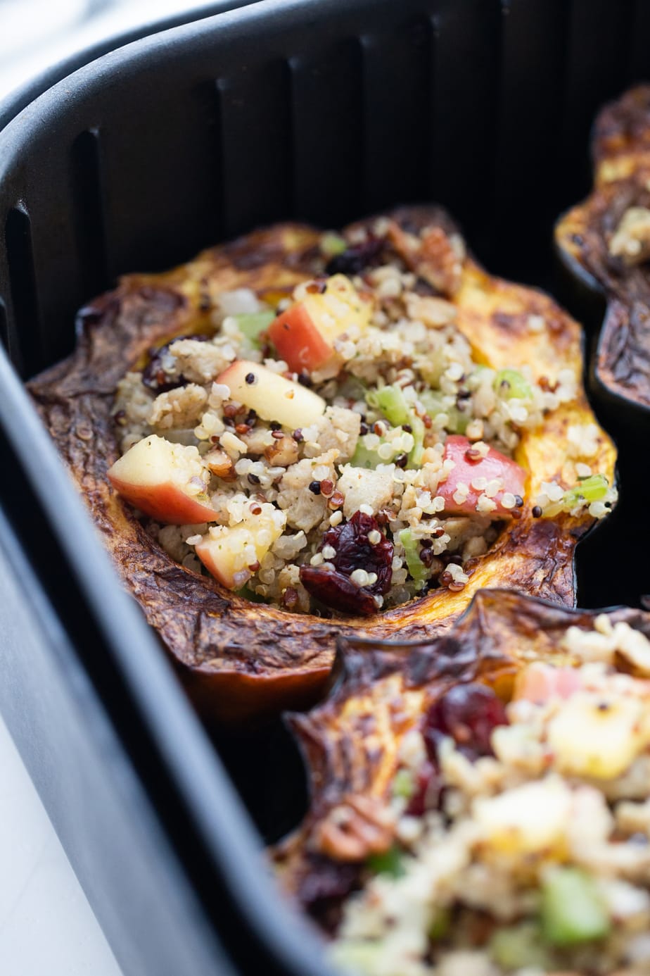 Close up photo: Acorn squash stuffed with apples, quinoa, sausage, and cranberries in the air fryer.