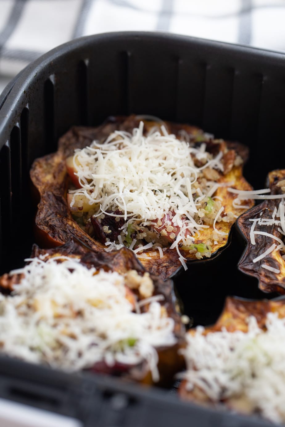 Air Fryer Stuffed acorn squash topped with Parmesan cheese, ready to be crisped.