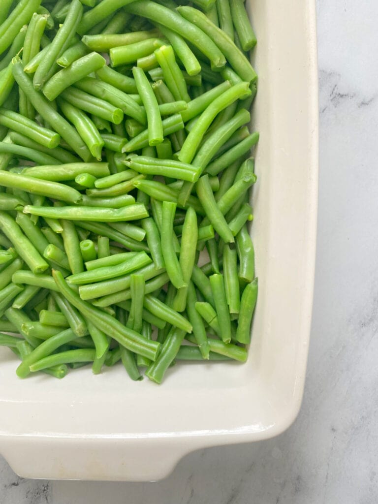 Overhead image: fresh cut green beans in a white casserole dish
