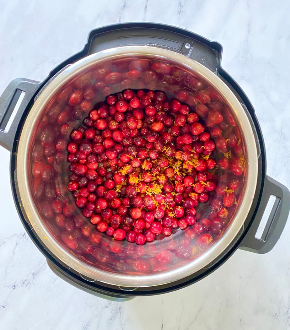 Overhead image: whole fresh cranberries and orange zest in an Instant Pot.