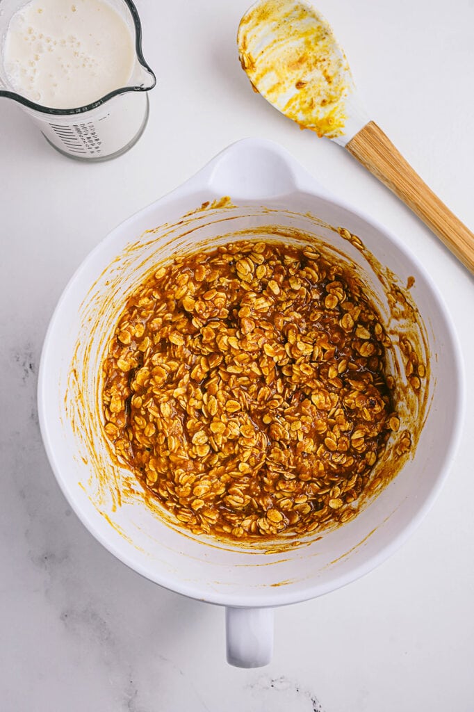 Overhead image: pumpkin oatmeal batter in a white bowl with a spatula off to the side.