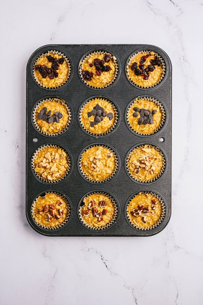 Overhead image: pumpkin oatmeal muffins with toppings, in a muffin tin