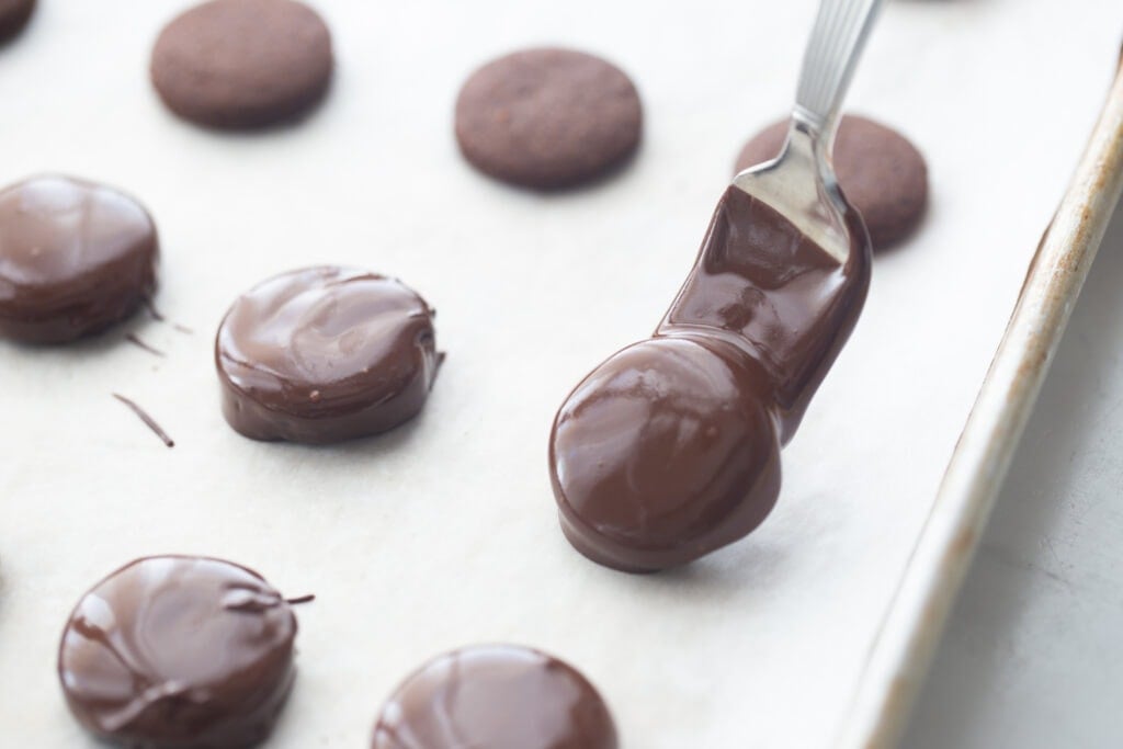 A close up of a chocolate covered thin mint cookie on a baking sheet lined with parchment paper  