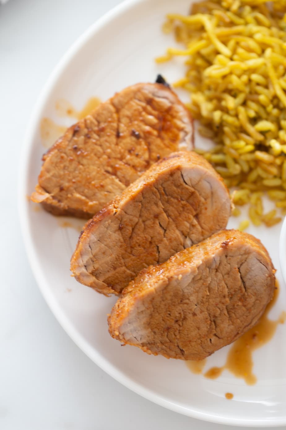 Overhead image of sliced pork tenderloin with delicious au jus drizzled over top!