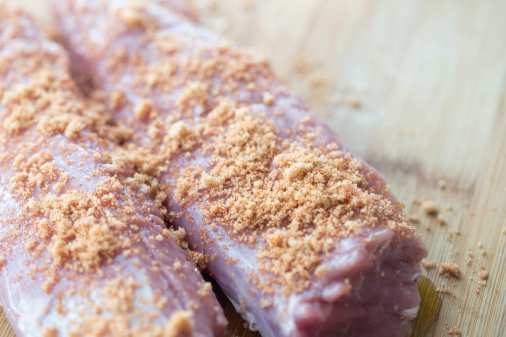 Raw pork tenderloin topped with a sweet and savory spice rub, ready for the air fryer.