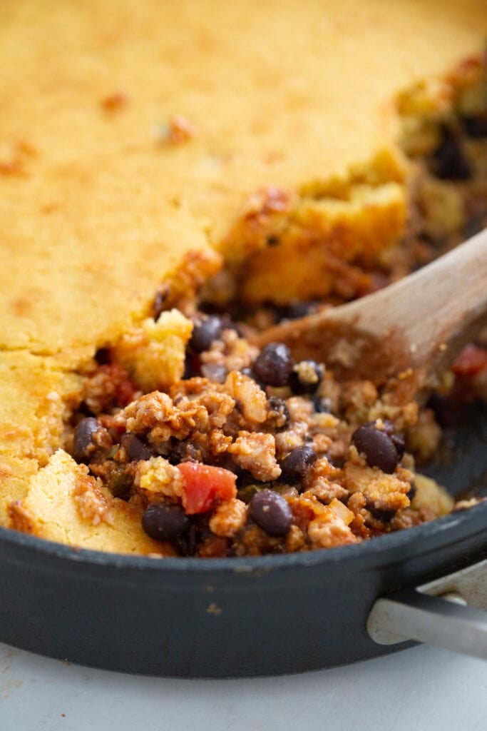 Close up photo of the chili filling with a cornbread topping.