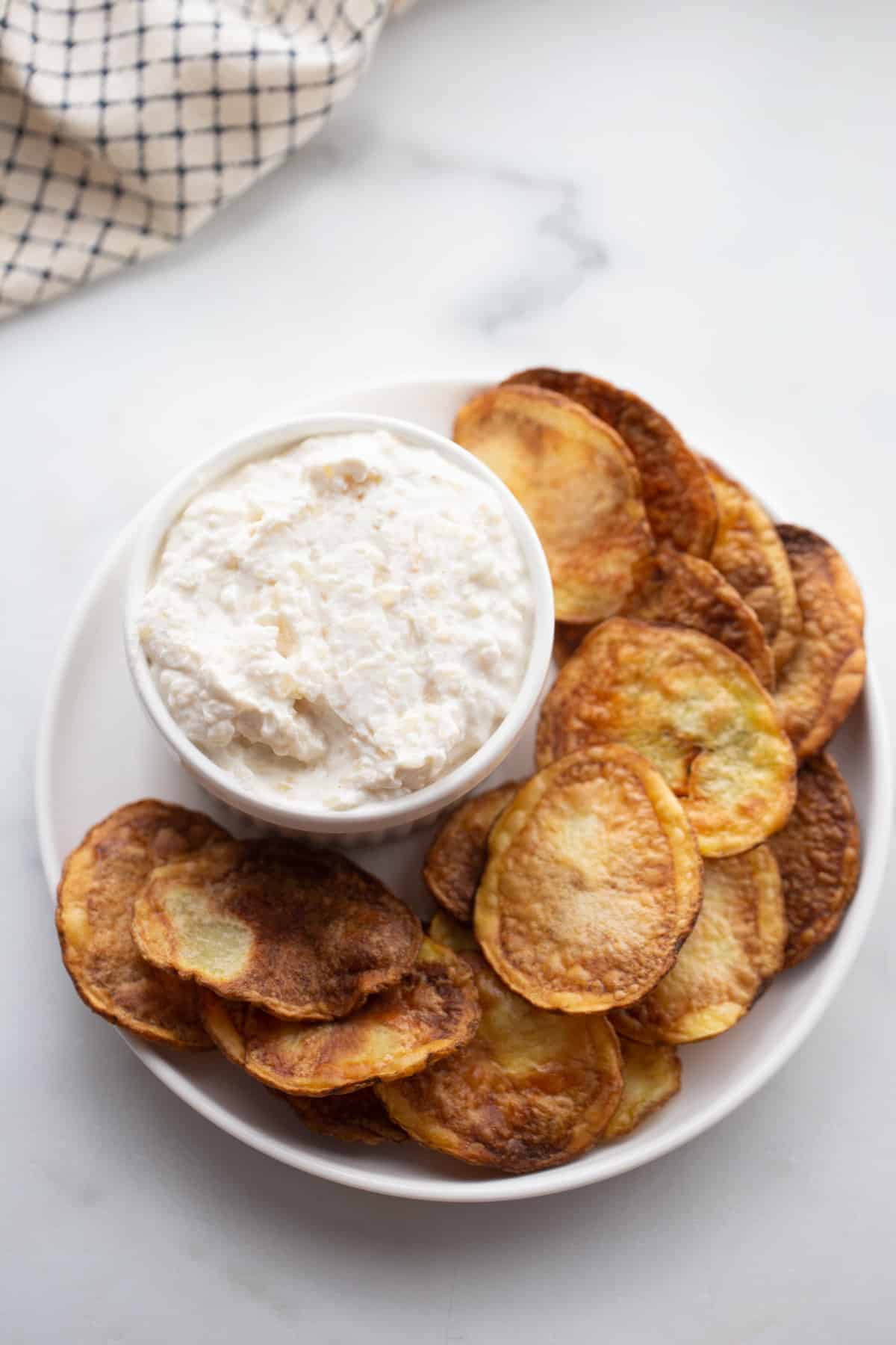 A plate of homemade air fryer potato chips with a side of Greek yogurt french onion dip. 