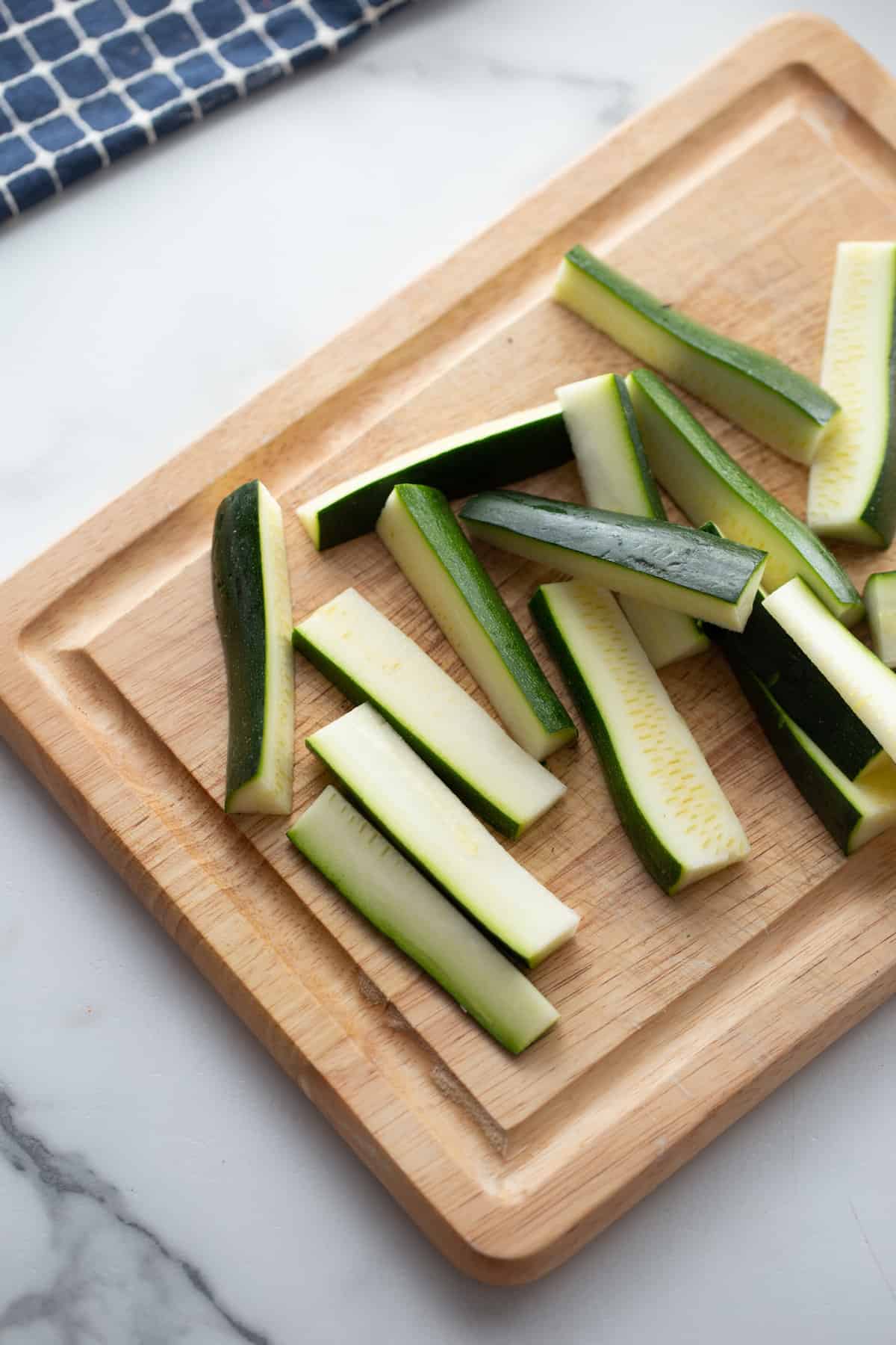 zucchini on a cutting board sliced into matchsticks or fries