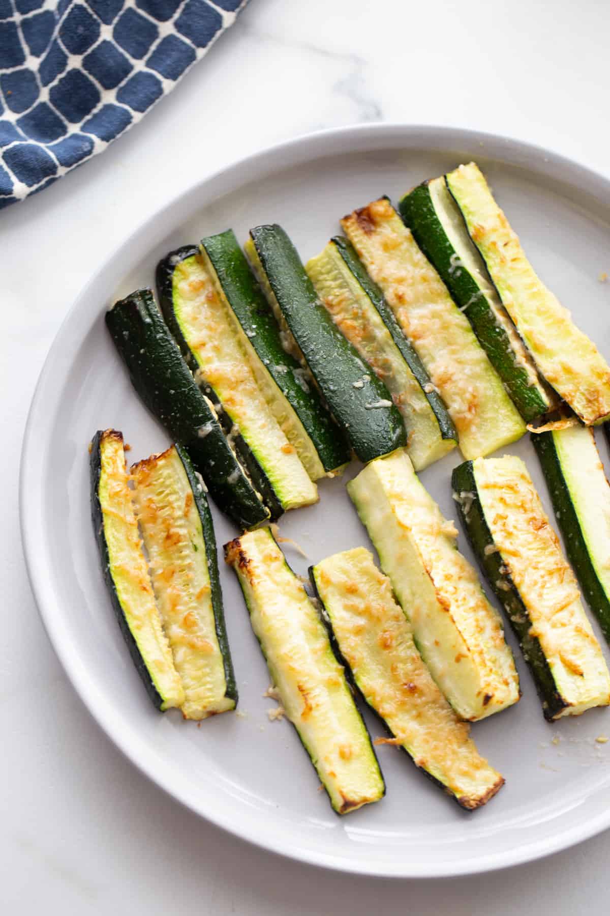 A plate of zucchini fries topped with crispy parmesan cheese
