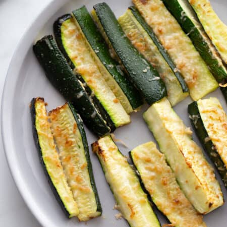 A plate of zucchini topped with crispy parmesan cheese