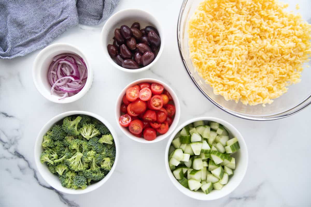 Overhead photo of small bowls of ingredients to make orzo salad