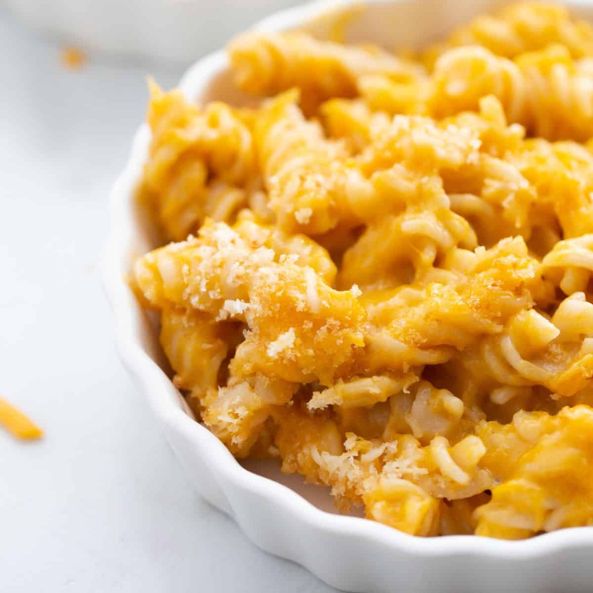 A close up shot of gluten free butternut squash pasta in a white bowl topped with breadcrumbs. 