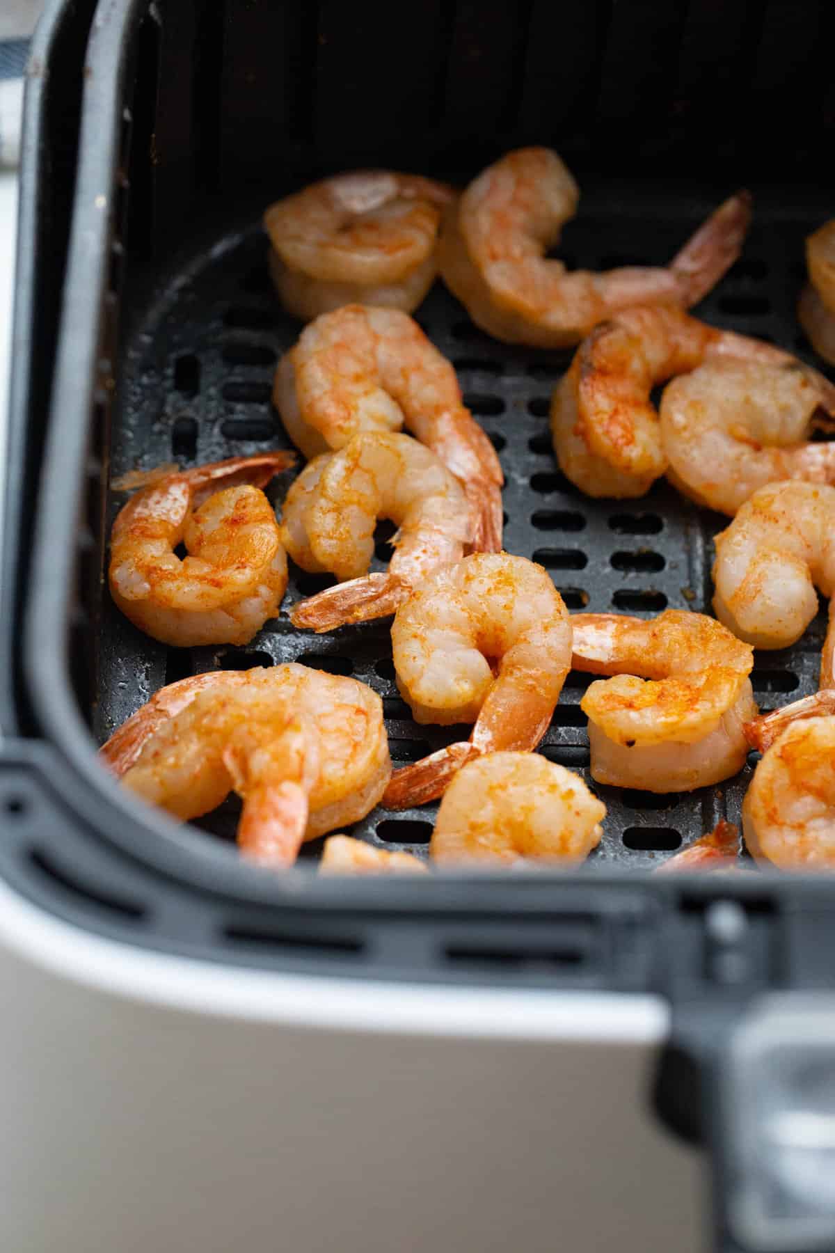 Cooked shrimp in an air fryer basket.