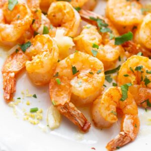Close up of Air Fryer Shrimp on a white platter with fresh herbs.