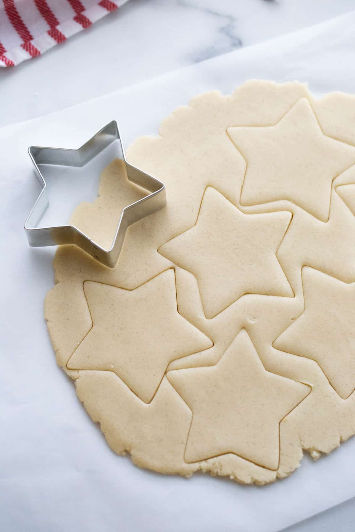 Gluten free cookie dough rolled out and cut into star shapes on parchment paper.