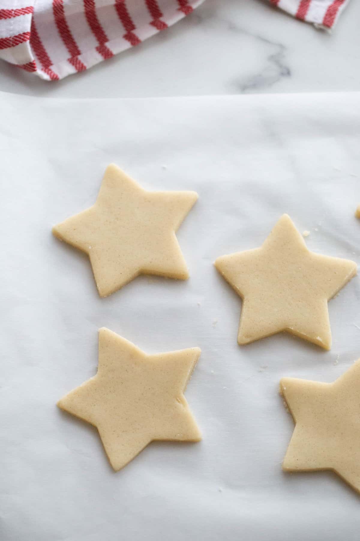 Four gluten-free sugar cookies on parchment paper before baking.