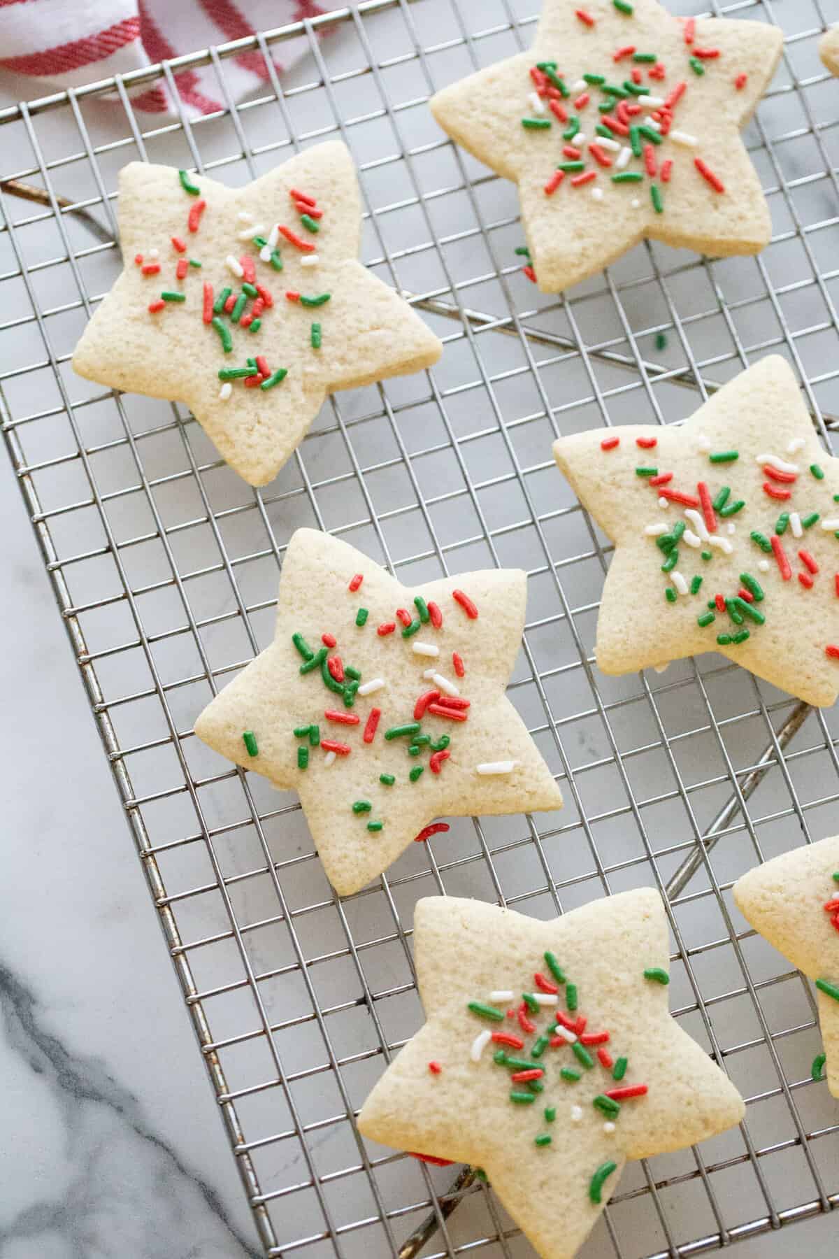 Six star shaped sugar cookies on a wire cooling rack.
