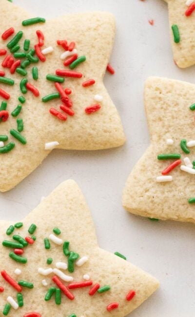 Close up of gluten free sugar cookies shaped like a star with red, green, and white sprinkles.