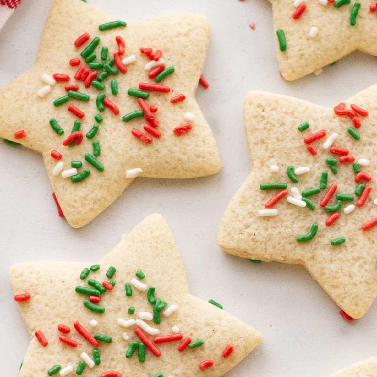 Close up of gluten free sugar cookies shaped like a star with red, green, and white sprinkles.