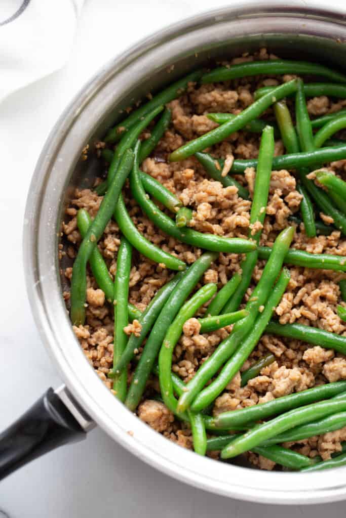A skillet with ground chicken and green beans.